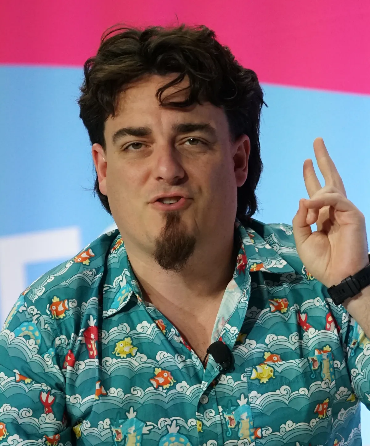 Palmer Luckey facing the camera at CES 2026 with wavy dark hair and a pointed chin goatee