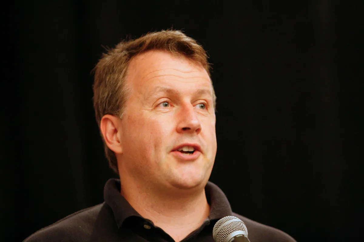 A detailed older portrait of Paul Graham speaking into a microphone