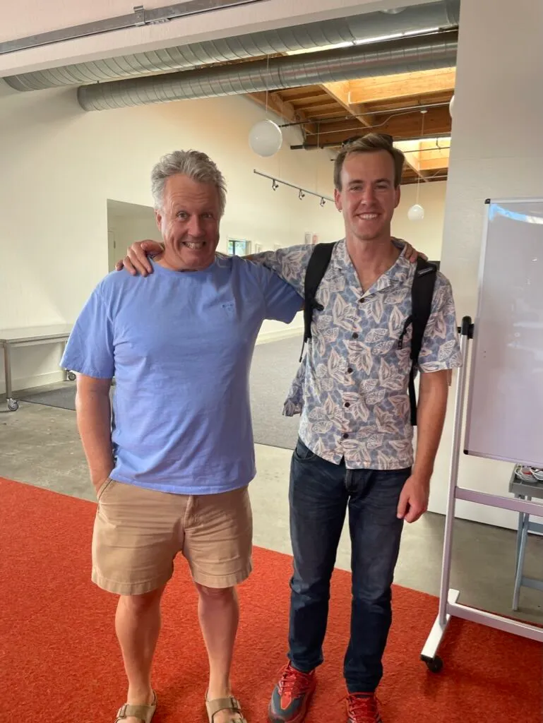 Paul Graham on the left beside Peter Mangan, wearing a blue shirt, tan shorts and sandals